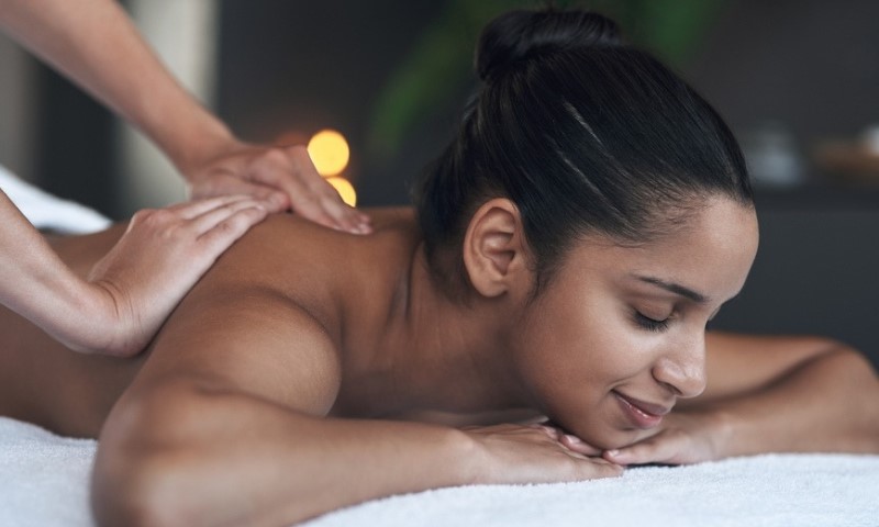 Snimak mlade žene koja dobija masažu leđa u spa centru